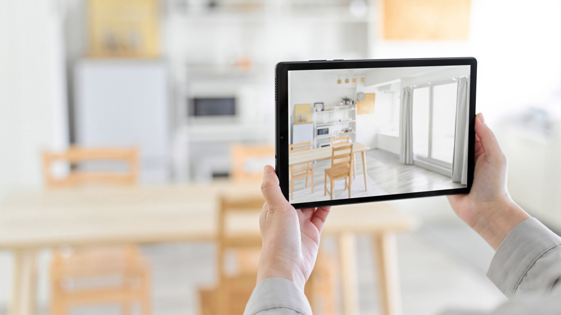 Osoba drži tablet s prikazom svijetle blagovaonice i kuhinje u aplikaciji za uređenje interijera.