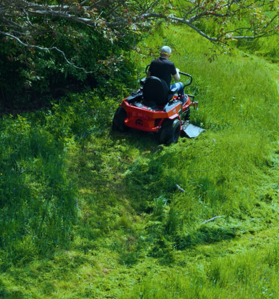 muškarac kosi visoku travu sa traktorskom kosilicom