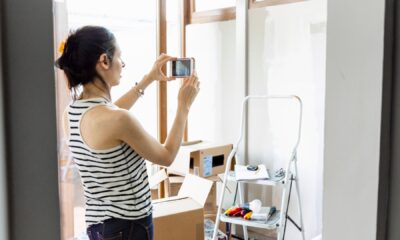 Žena mobitelom fotografira stanje stana tijekom useljenja, uz kutije i ljestve u prostoriji.