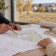 Arhitekt i investitor pregledavaju plan kuće i smještaj na zemljištu prije postupka izdavanja lokacijske dozvole.